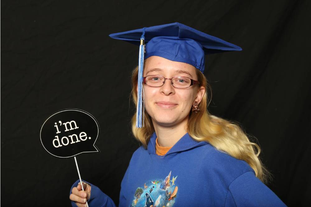 woman in a graduation cap using props at photobooth